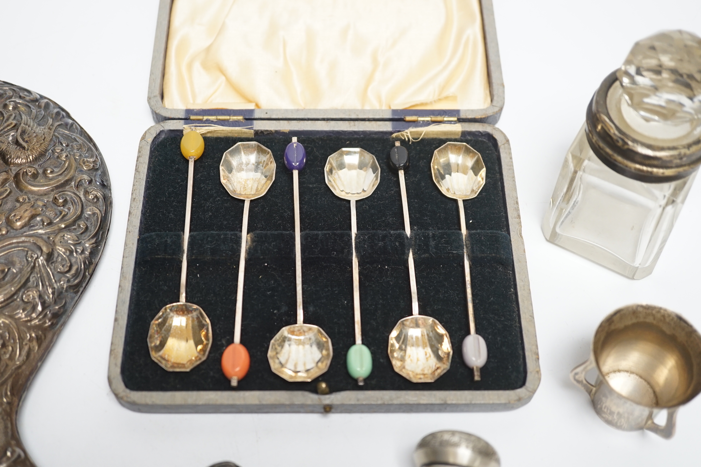 A Hanau silver novelty figural pepperette and other small silver including a silver mounted hand mirror, scent bottles and a small tyg and a cased set of plated spoons.